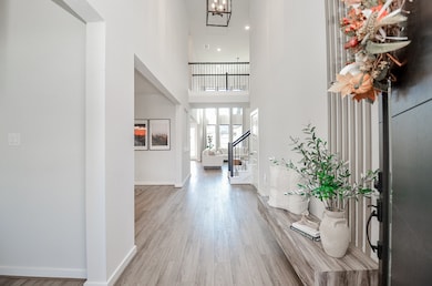 Welcome to an elegant foyer featuring soaring ceilings, abundant natural light, and a stunning open staircase—perfect for a grand entrance.