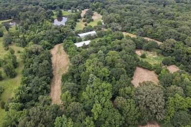 Aerial overview of property's location with a nearby body of water, a heavily wooded area, and rural landscape