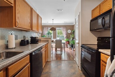 Kitchen with dark hardwood / wood-style floors, black appliances, pendant lighting, ornamental molding, and decorative backsplash