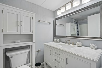 Bathroom featuring toilet, a textured wall, curtai