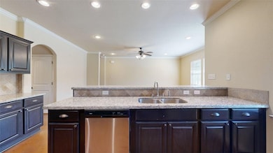 Kitchen with crown molding, stainless steel dishwasher, light stone counters, decorative backsplash, and recessed lighting