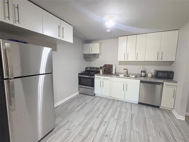 Kitchen featuring appliances with stainless steel finishes, white cabinets, wood finish floors, and under cabinet range hood