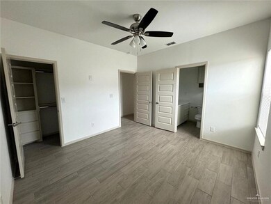 Unfurnished bedroom featuring wood finished floors, a spacious closet, baseboards, and ensuite bath