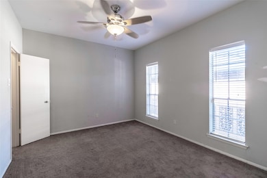Carpeted spare room featuring a ceiling fan and baseboards