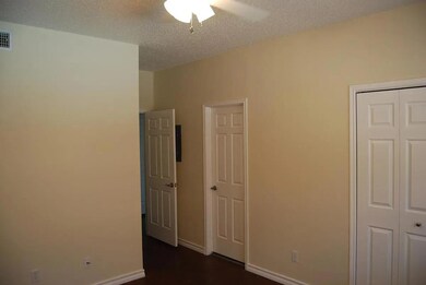 Unfurnished bedroom featuring a textured ceiling, a ceiling fan, a closet, and dark wood-style flooring