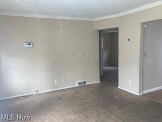Unfurnished room featuring crown molding and a tex