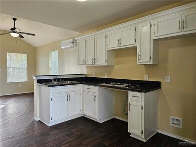 Kitchen with a wall mounted AC, white cabinets, dark hardwood / wood-style floors, and ceiling fan