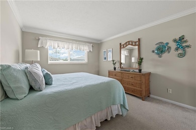 Bedroom featuring ornamental molding, a textured ceiling, and carpet