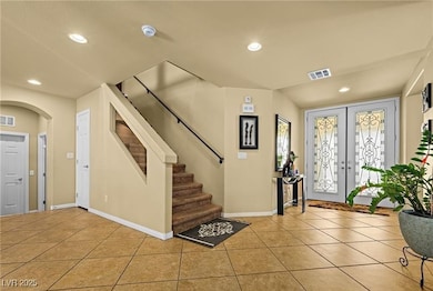 Tiled foyer entrance with french doors, recessed lighting, stairway, and arched walkways