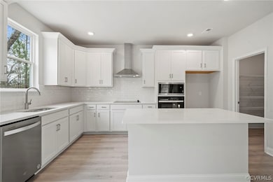 Kitchen featuring wall chimney range hood, sink, l
