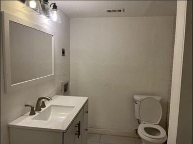Bathroom with toilet, vanity, baseboards, visible 