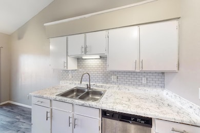 Kitchen with dishwasher, sink, lofted ceiling, whi
