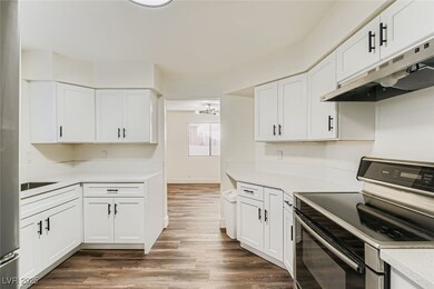 Kitchen with stainless steel electric range oven and white cabinetry