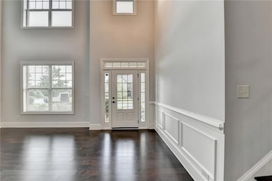 Foyer entrance with a wainscoted wall, dark wood-s