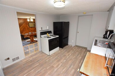 Kitchen featuring light countertops, electric range, white cabinetry, light wood-type flooring, and wood walls