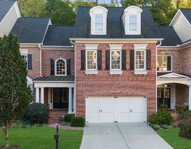 Georgian-style home featuring concrete driveway, brick siding, a front yard, and an attached garage