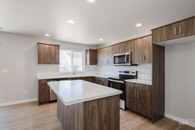 Kitchen with appliances with stainless steel finishes, light countertops, a kitchen island, light wood finished floors, and recessed lighting