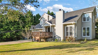 Back of property with a shingled roof, a yard, a chimney, and a deck