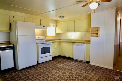 Kitchen featuring white appliances, under cabinet range hood, ceiling fan, and cream cabinets