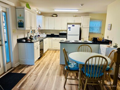 Kitchen featuring freestanding refrigerator, stainless steel microwave, black dishwasher, light wood-style flooring, and a sink