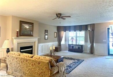 Carpeted living room with a textured ceiling, ceiling fan, and a gas fireplace