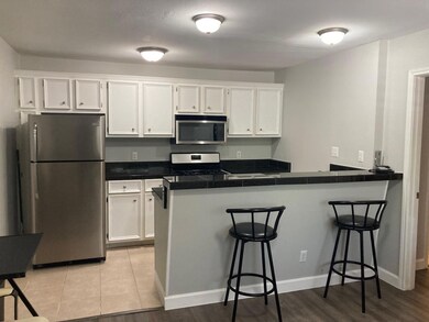 Kitchen featuring a peninsula, white cabinets, st