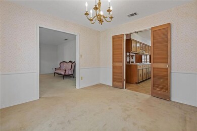 Unfurnished dining area featuring a chandelier, light colored carpet, a wainscoted wall, and wallpapered walls