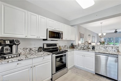 Kitchen featuring white cabinets, stainless steel appliances, backsplash, a sink, and custom granite countertops