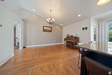 Dining space featuring light wood-style flooring, recessed lighting, a chandelier, arched walkways, and high vaulted ceiling