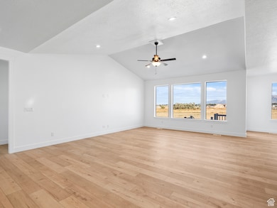 Unfurnished living room with light wood finished floors, lofted ceiling, a textured ceiling, a ceiling fan, and recessed lighting