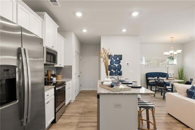 Kitchen with stainless steel appliances, light wood finished floors, decorative backsplash, white cabinetry, and a breakfast bar