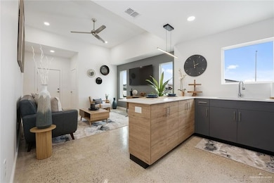 Kitchen featuring ceiling fan, decorative light fixtures, sink, and kitchen peninsula