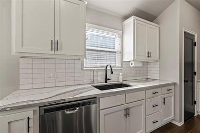 Kitchen with light stone counters, a sink, white c