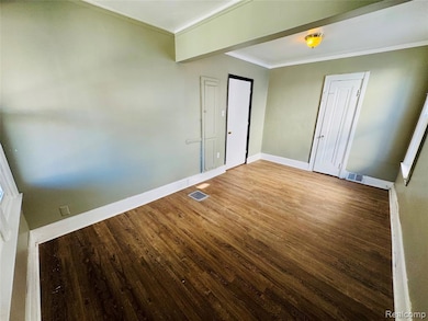 Unfurnished bedroom featuring crown molding, wood finished floors, and a closet
