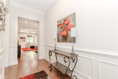 Hallway with light wood-style flooring, ornamental molding, and wainscoting