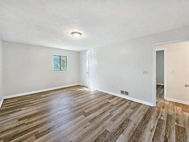 Hallway with wood finished floors and a textured ceiling