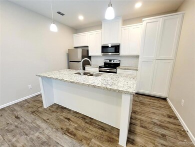 Kitchen with backsplash, stainless steel appliances, white cabinets, a kitchen island with sink, and decorative light fixtures