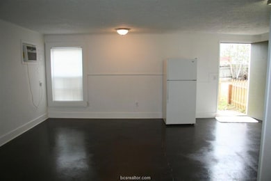Unfurnished room with baseboards, a wall unit AC,
