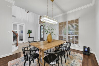 This dining area features a modern, it has ample natural light from large windows and a stylish, contemporary chandelier.  enhancing the home's inviting atmosphere.