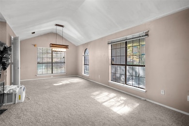 Unfurnished living room featuring carpet floors, vaulted ceiling, and a chandelier