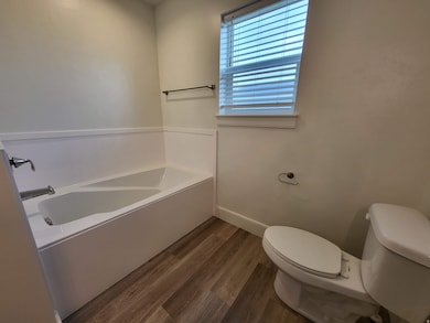 Full bathroom featuring a bath and dark wood-style floors