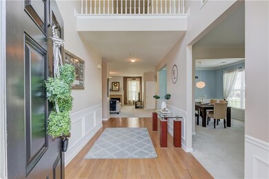 Entryway featuring wood finished floors, wainscoting, a decorative wall, a fireplace, and a high ceiling