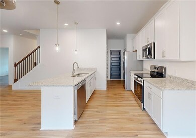 Kitchen featuring sink, white cabinets, light ston