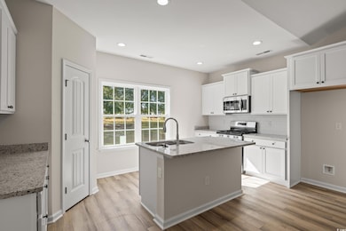 Kitchen with white cabinets, sink, an island with 