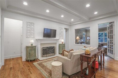 Living room featuring wood finished floors, recessed lighting, a fireplace with raised hearth, and beamed ceiling