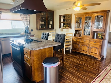 Kitchen featuring ventilation hood, electric range, dark wood finished floors, a center island, and brown cabinetry