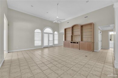 Unfurnished living room with ceiling fan, light tile patterned floors, a high ceiling, and ornamental molding