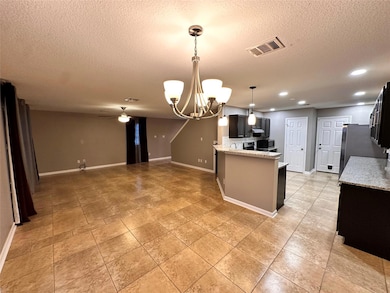 Kitchen with a textured ceiling, baseboards, a ch