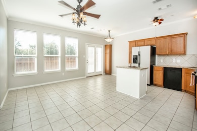 Kitchen featuring ceiling fan, brown cabinetry, light tile patterned floors, ornamental molding, and a kitchen island