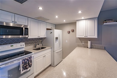 Kitchen with tasteful backsplash, sink, white cabinets, and white appliances